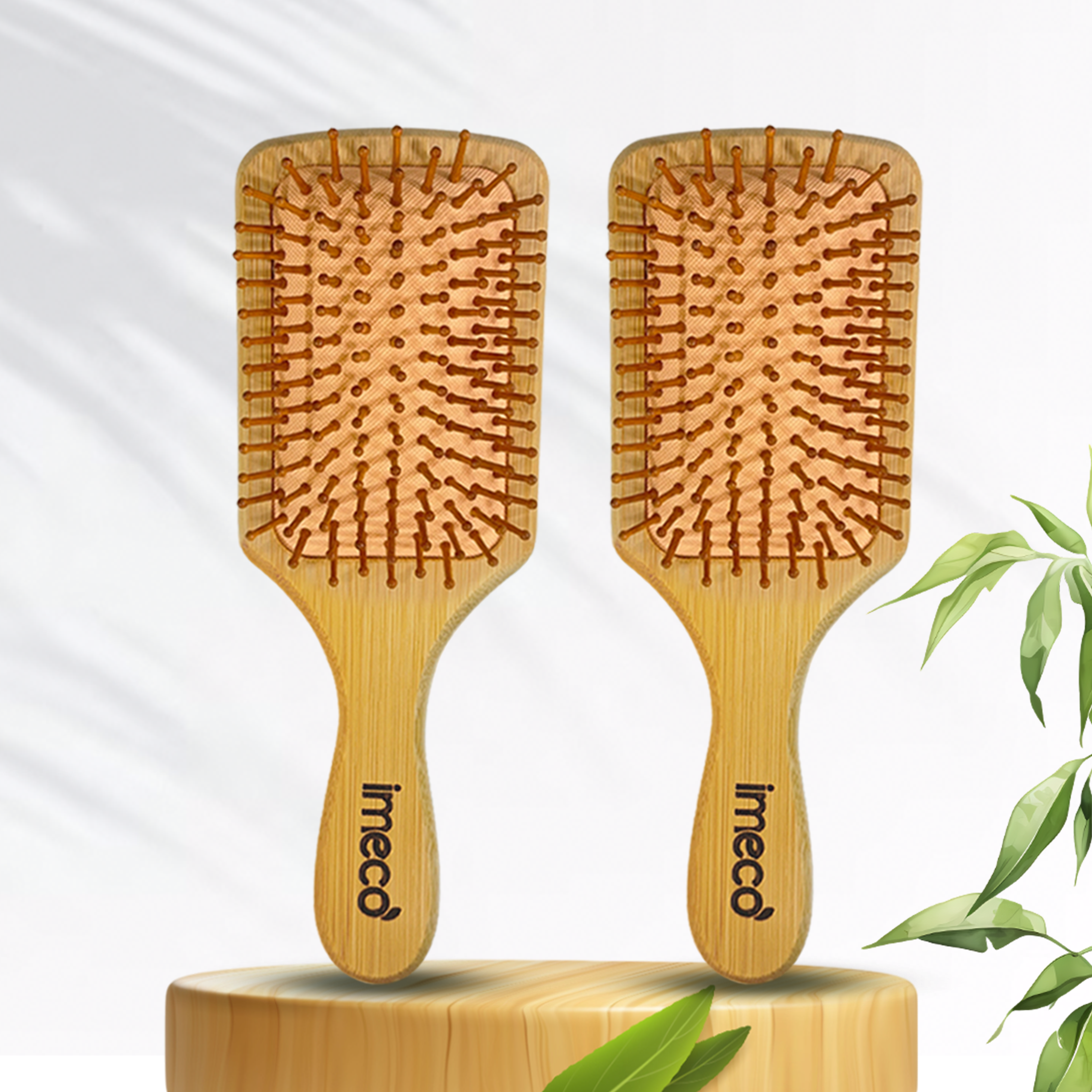 Two bamboo hairbrushes with 'imeco' branding on a light gray background with green leaves.