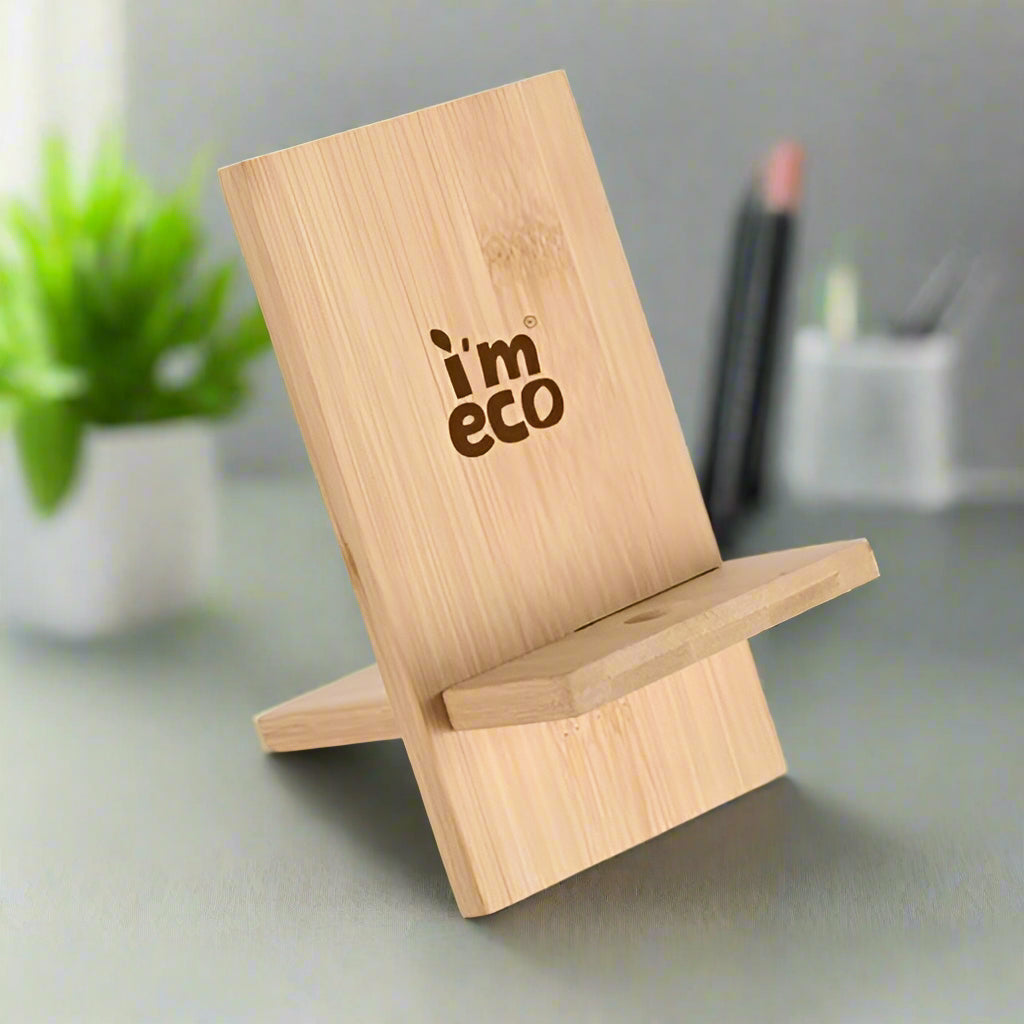 IMECO bamboo mobile stand with the text 'imeco' printed on it, displayed on a desk with a plant and pens in the background.